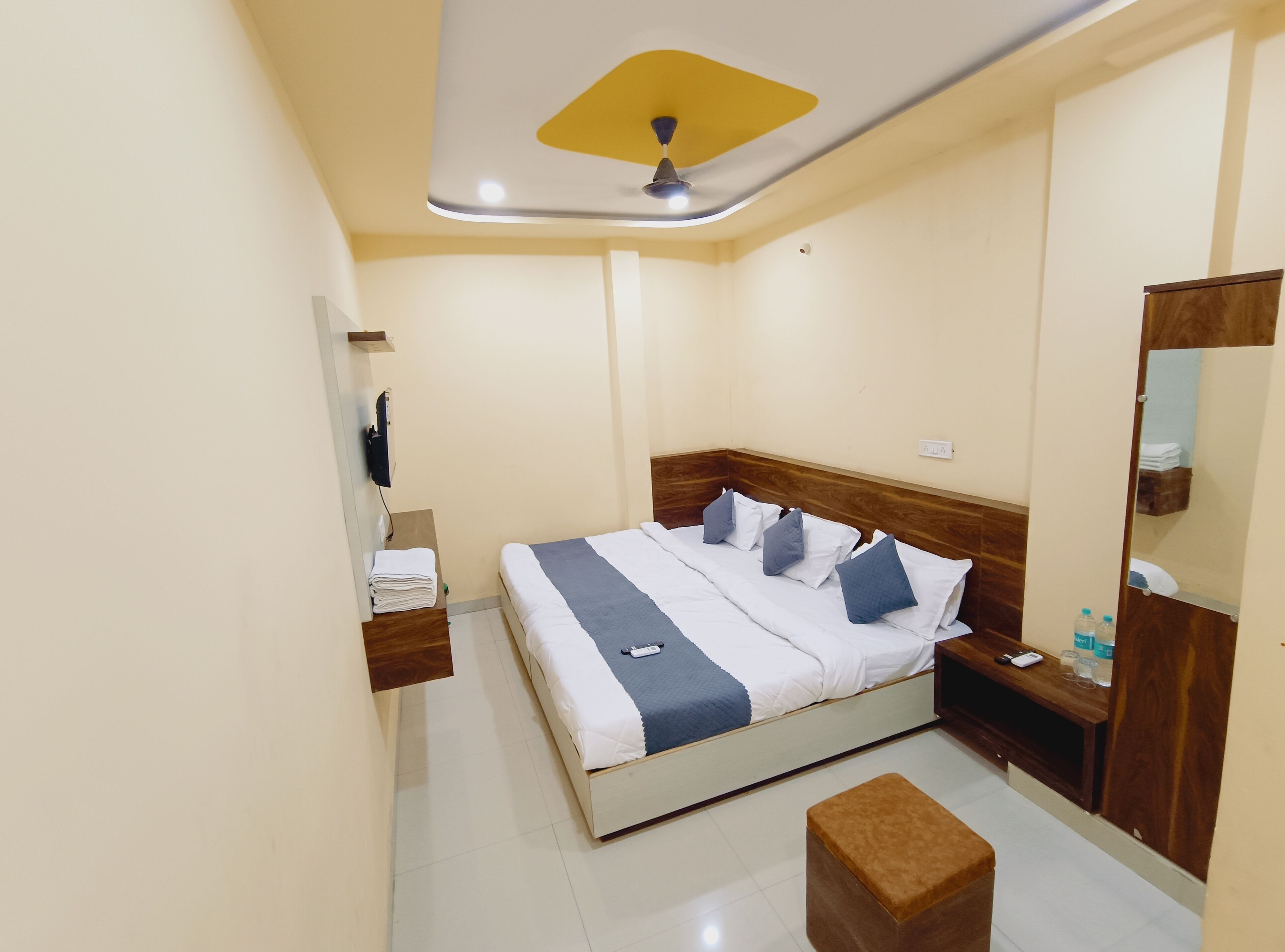 Una habitación de hotel con cama, mesita de noche y espejo.