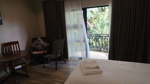 A hotel room with a bed, a chair, a table, and a view of the outdoors. - Unitas Guesthouse (Centurion)