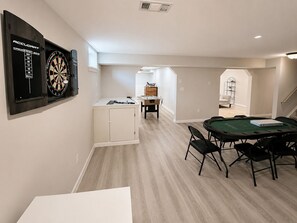 Una habitación con dardos, mesa de futbolín y mesa de billar.