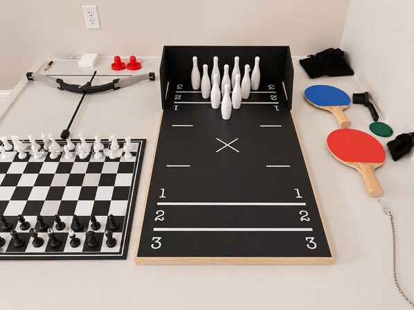 A table set up with a chessboard, a bowling alley, and two table tennis paddles.