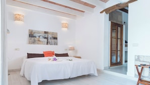 Un dormitorio con una cama, dos lámparas de pared, un cuadro y una viga de techo de madera.