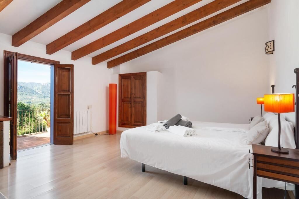 Ein Schlafzimmer mit Bett, Holzbalken, einem Fenster und Blick.