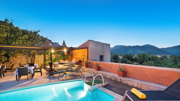 Piscina en la azotea con vistas a montañas, mobiliario exterior y zona cubierta con mesas y sillas.