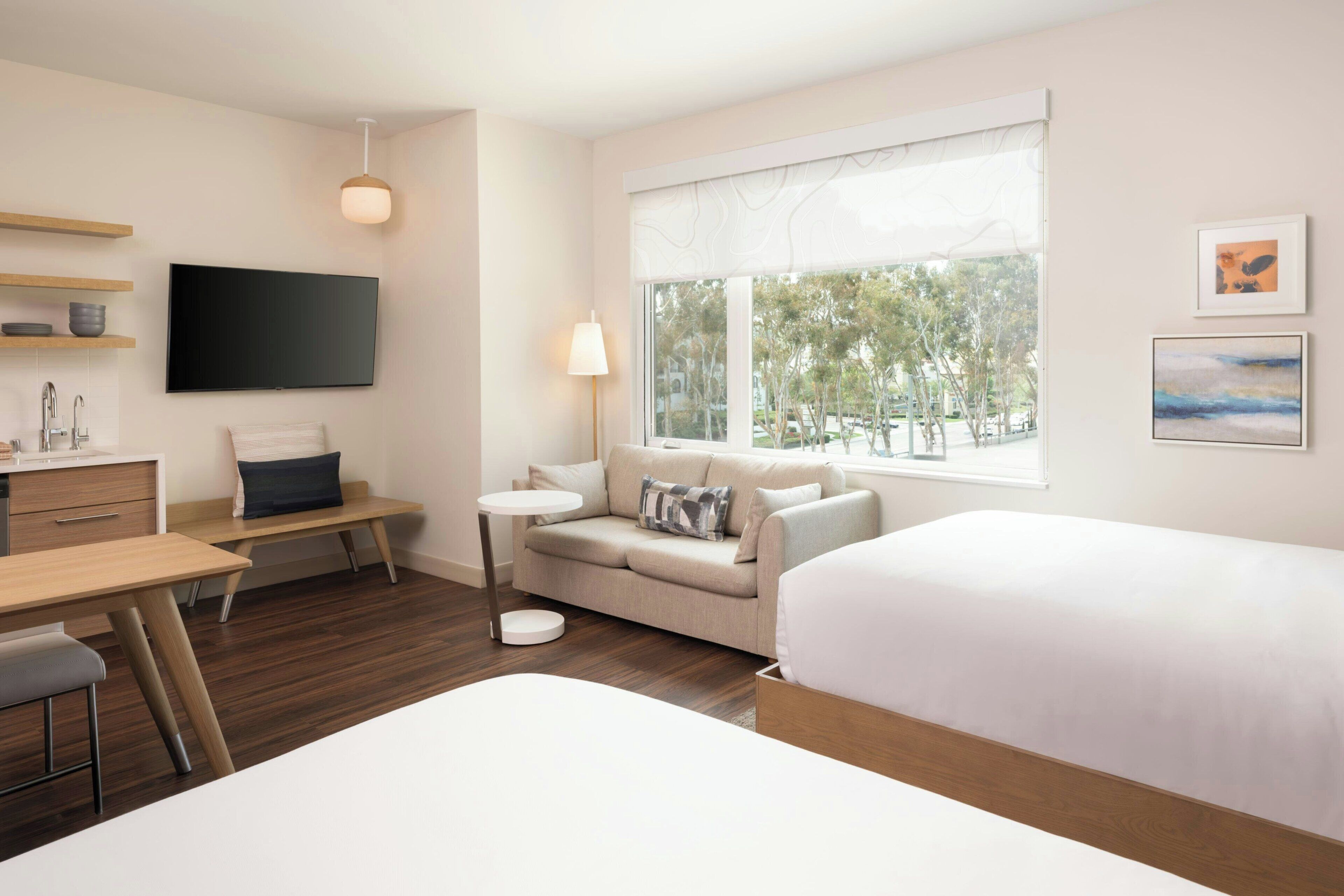 Ein modernes Hotelzimmer mit Bett, Sofa, Schreibtisch und Fernseher.