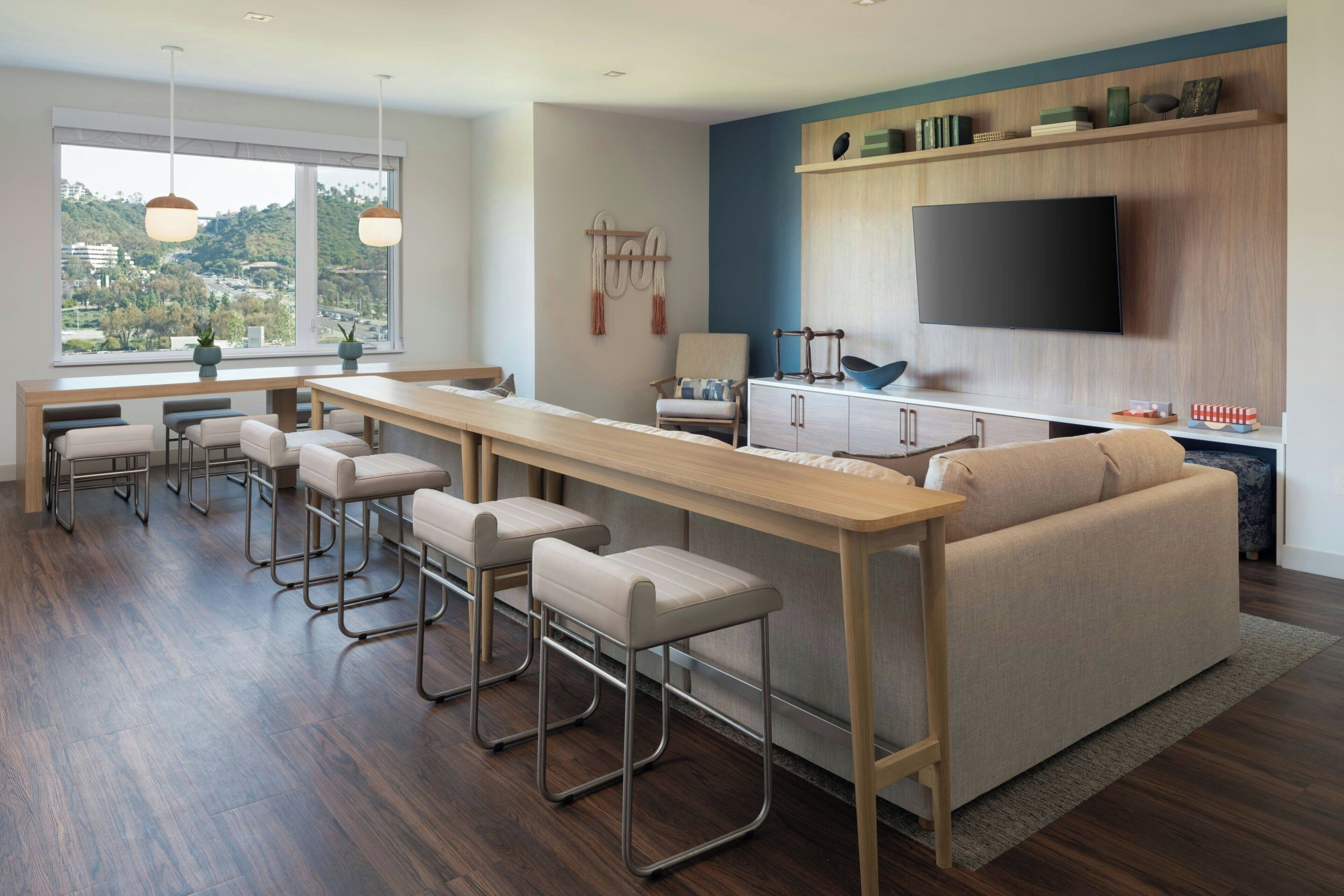 A modern kitchen with a bar area, a sofa, and a TV.