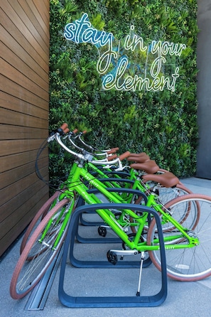Una bicicleta verde estacionada en un soporte con un cartel que dice 'stay in your element' al fondo.