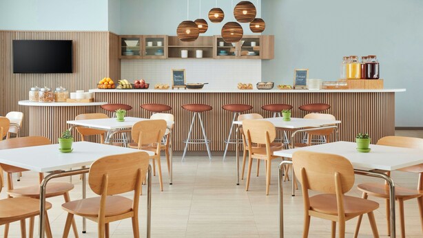 Una cucina moderna con isola centrale, sedie di legno e un televisore a schermo piatto montato a parete.