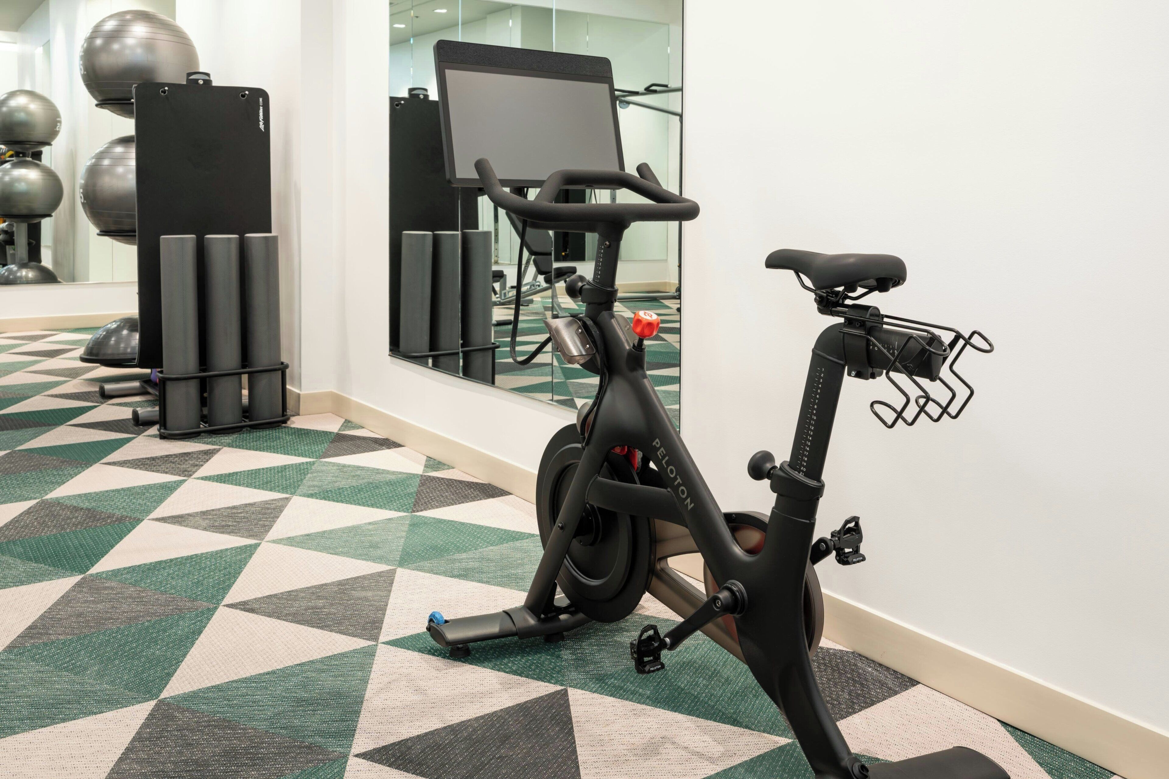 A stationary bike in a gym with a mirrored wall and exercise balls in the background.