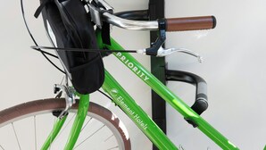 Una bicicletta verde con una borsa nera fissata al portapacchi posteriore.