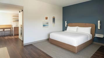 A modern bedroom with a large bed, a wooden headboard, a small desk, and a chair.
