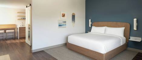 Un dormitorio moderno con una cama grande, cabecera de madera, un escritorio pequeño y una silla.
