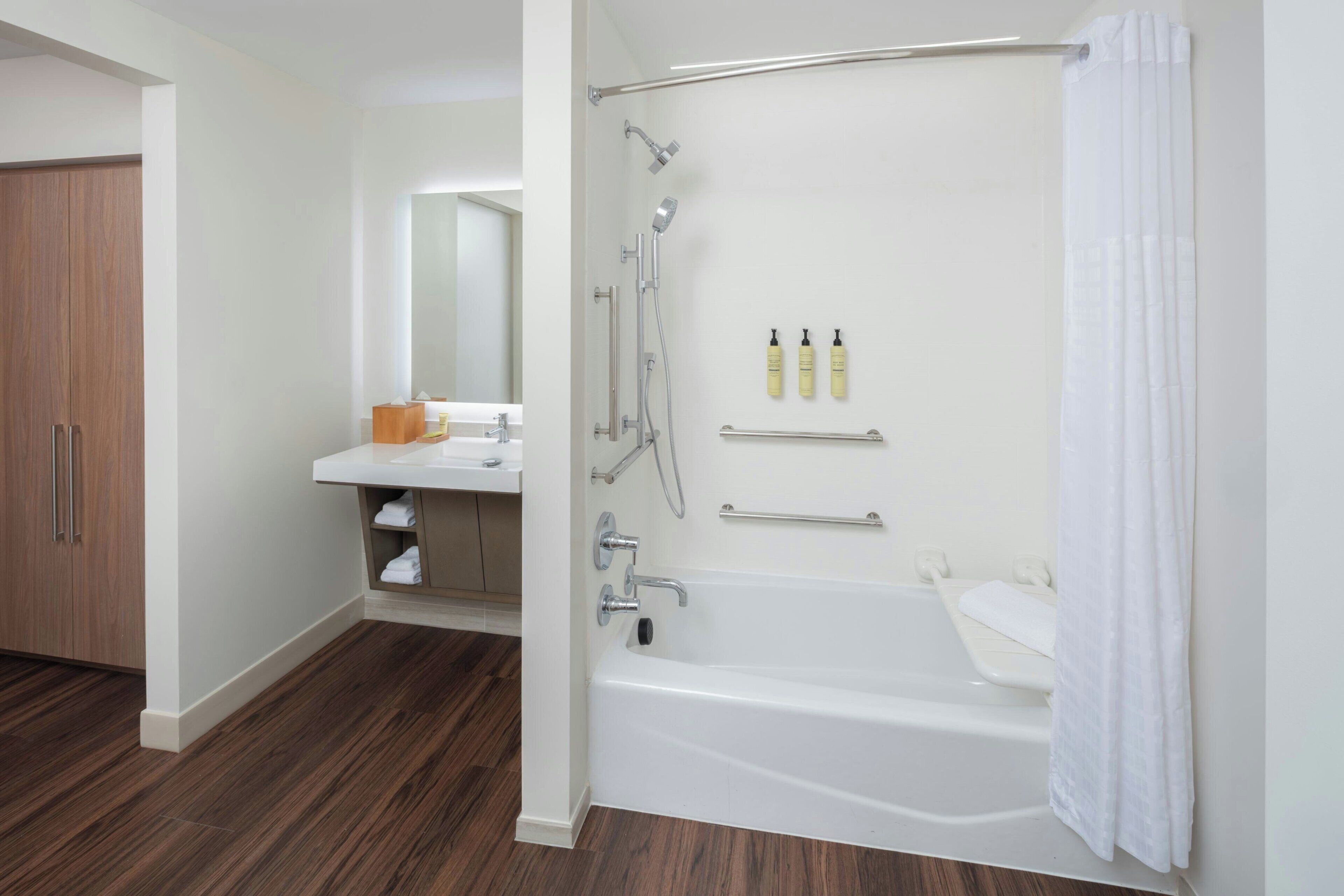 Un baño moderno con bañera, ducha y tocador con espejo.