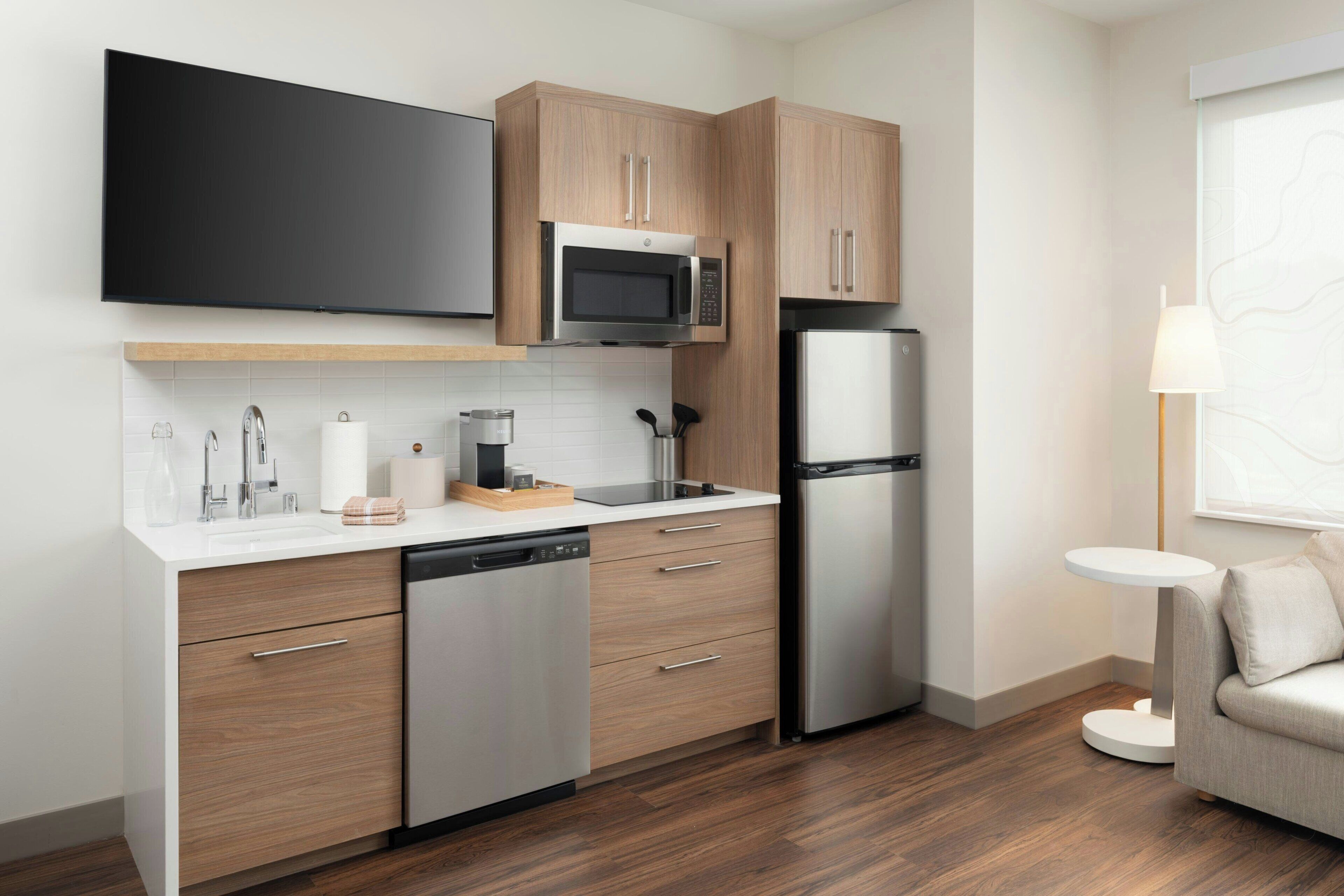 A modern kitchen with wooden cabinets, a built-in microwave, a stainless steel refrigerator, and a dishwasher.