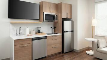 A modern kitchen with wooden cabinets, a built-in microwave, a stainless steel refrigerator, and a dishwasher.