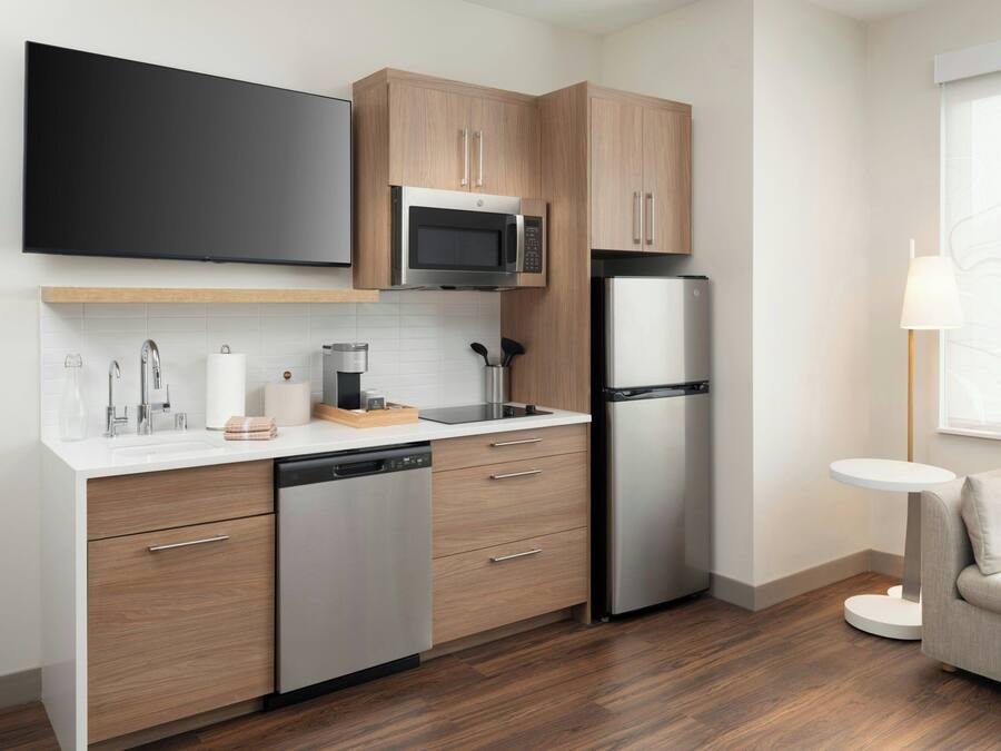A modern kitchen with wooden cabinets, a built-in microwave, a stainless steel refrigerator, and a dishwasher.