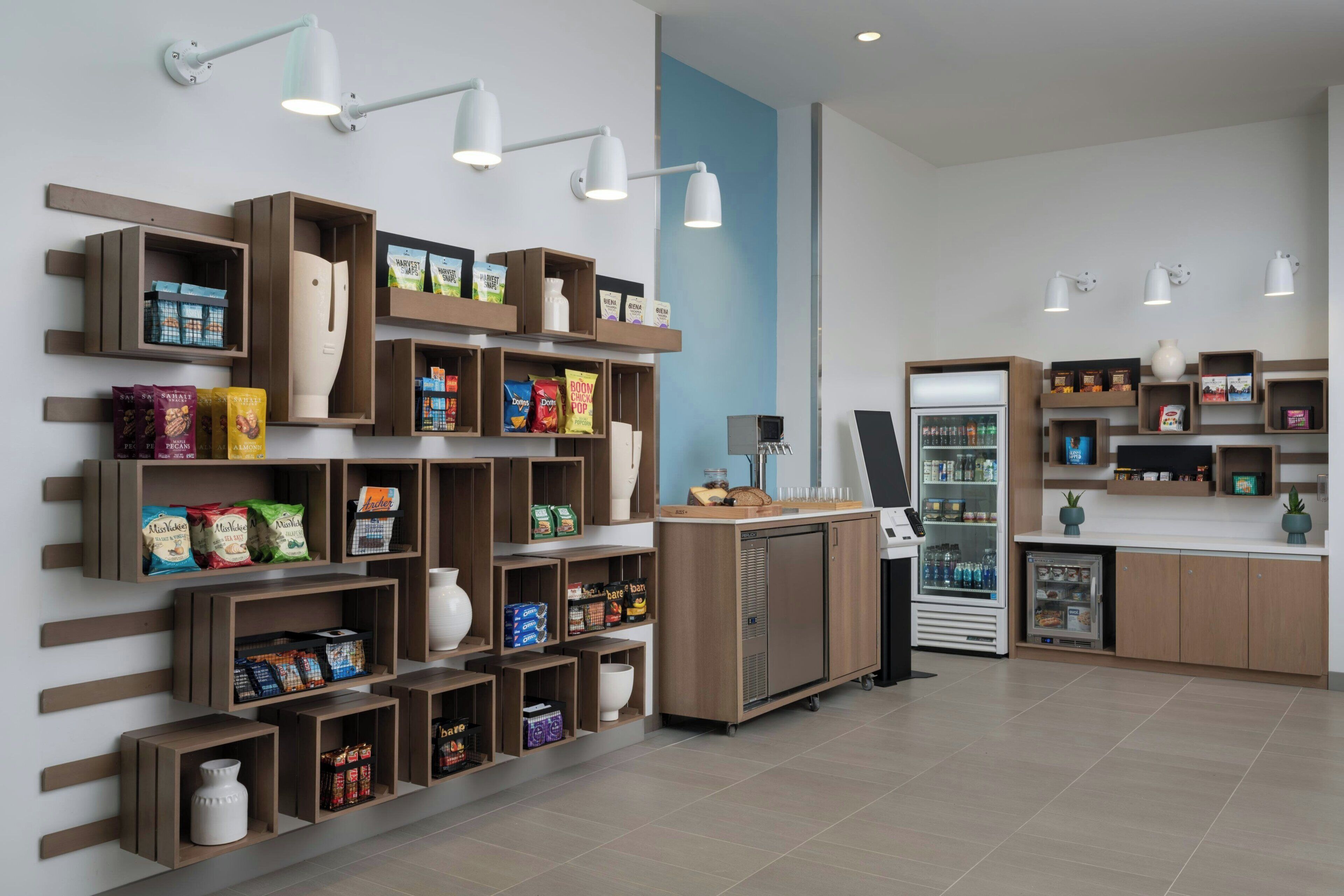 Een moderne, overzichtelijke snackbar met diverse snacks en dranken, een koffieapparaat en een koelkast.