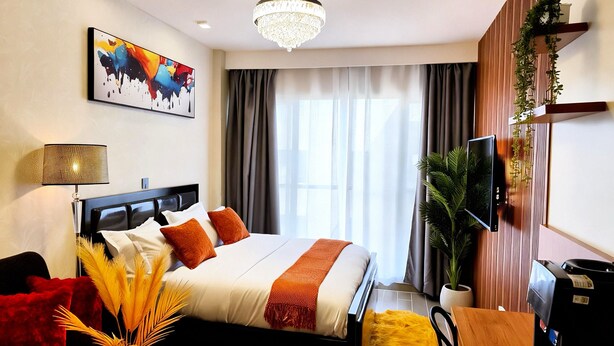 A modern hotel room with a bed, a chandelier, a painting, a TV, and a plant. - Welcome to your modern, peaceful escape just minutes from the airport &CBD (Nairobi)