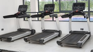 Three stationary treadmills in a room with large windows, a tiled floor, and a white wall. - Welcome to your modern, peaceful escape just minutes from the airport &CBD (Nairobi)
