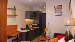 A modern kitchen with a built-in stove, a dining area with a wooden table and chairs, and a living room with a sofa and a lamp. - Welcome to your modern, peaceful escape just minutes from the airport &CBD (Nairobi)