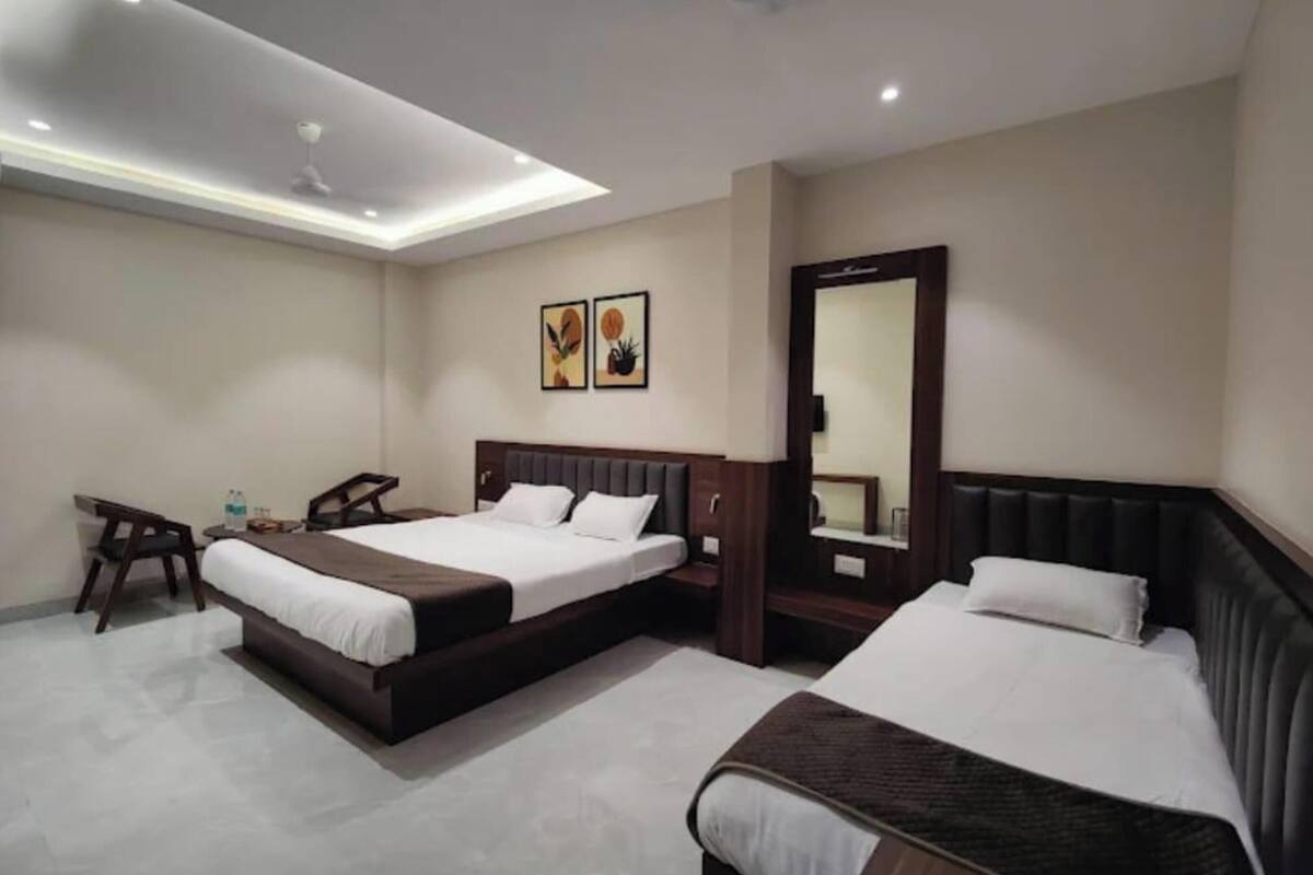 Habitació d'hotel amb dos llits, un escriptori, una cadira, un mirall i obra d'art a la paret.