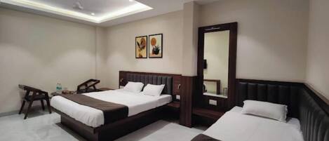 A hotel room with two beds, a desk, a chair, a mirror, and artwork on the wall.