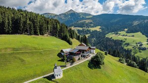 Un refugio de montaña con un edificio grande, una extensión más pequeña y una estructura que recuerda a una iglesia.