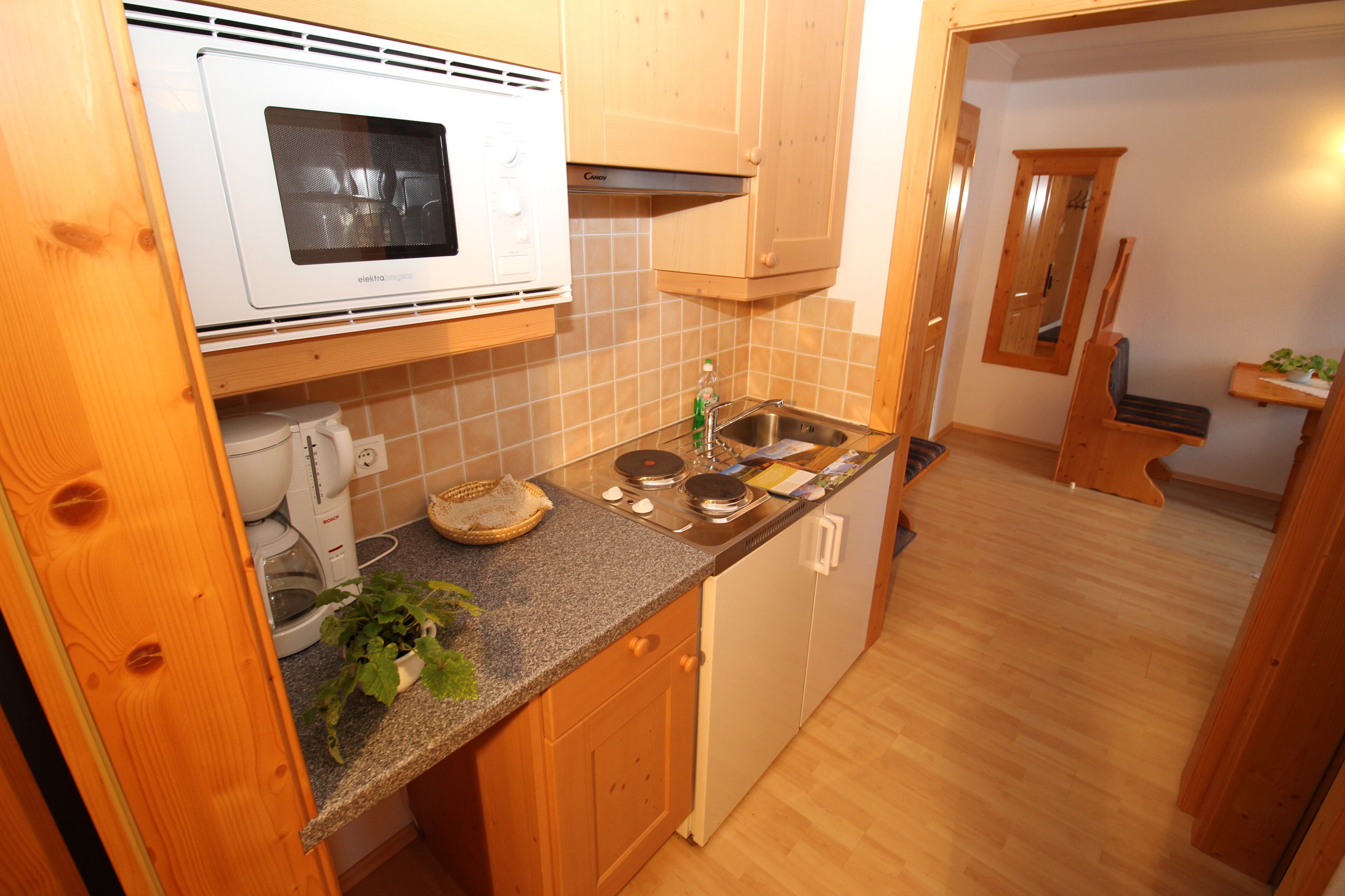 A compact kitchen with a microwave, stove, sink, and wooden cabinets.