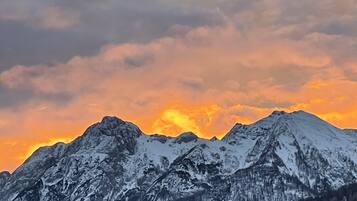 A mountain range with snow-covered peaks and a sunset sky.