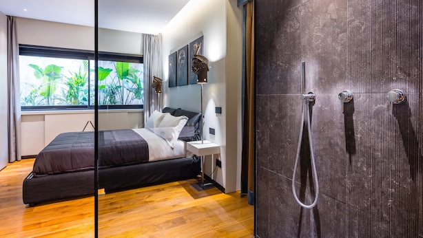 A modern bedroom with a bed, bedside table, and a large window with a view of greenery. - Santopaolo Boutique Apartment  (Naples)