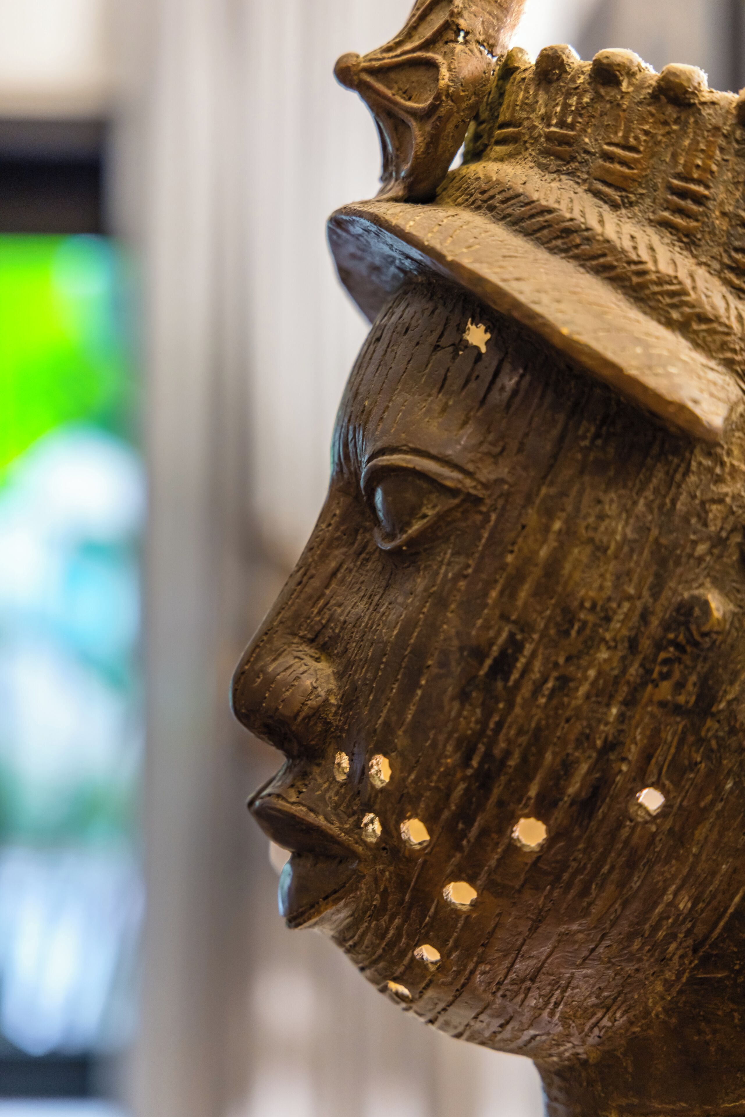 A close-up of a wooden sculpture with a crown and a hat.