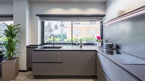 A modern kitchen with a built-in sink, a window with a view of buildings, and a potted plant. - Santopaolo Boutique Apartment  (Naples)