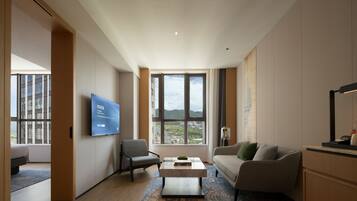 Una sala de estar moderna con un ventanal grande, un televisor de pantalla plana, un sofá, un sillón y una mesa de centro.