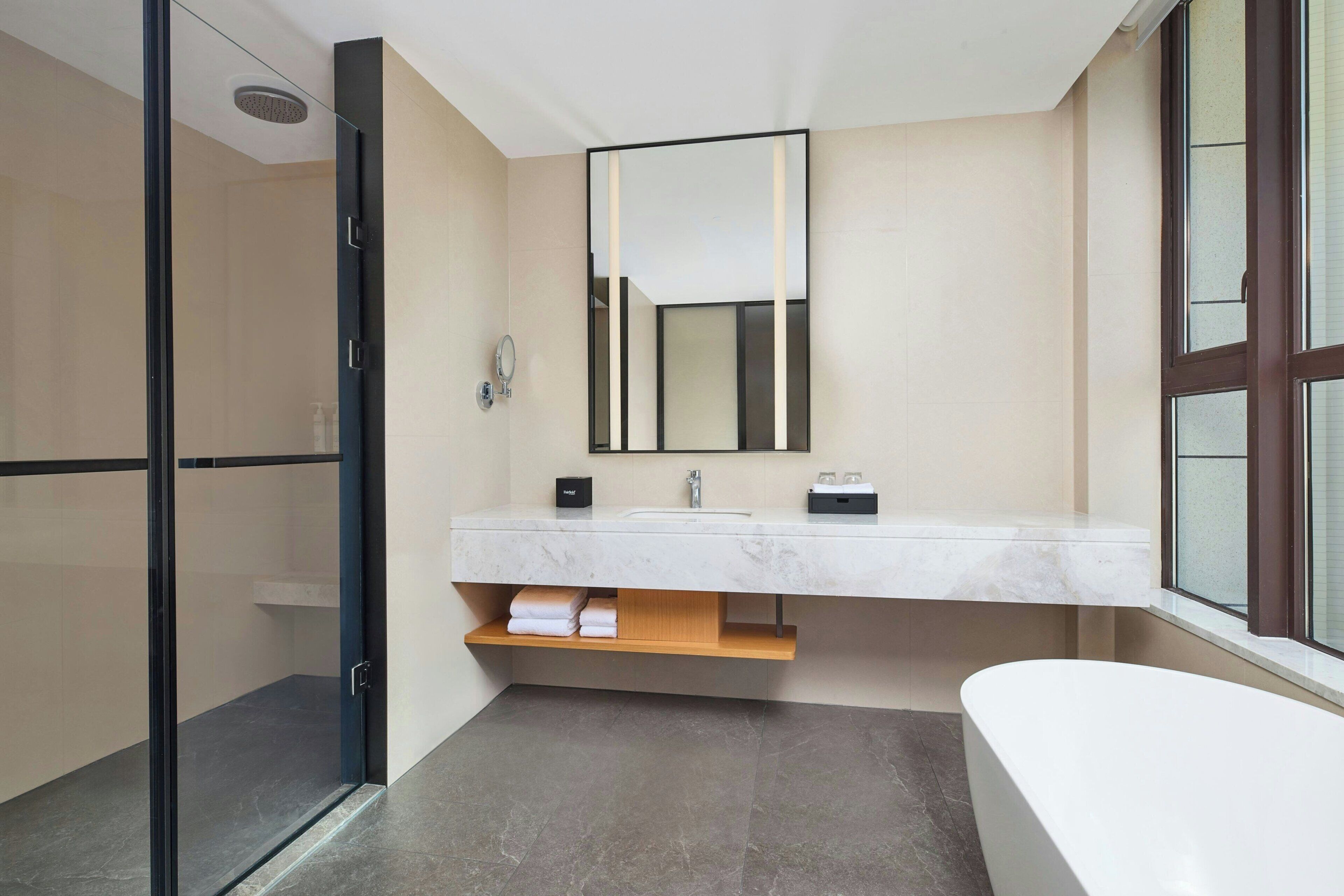Un baño moderno con cabina de ducha de vidrio, un espejo grande, un lavamanos blanco y una bañera.