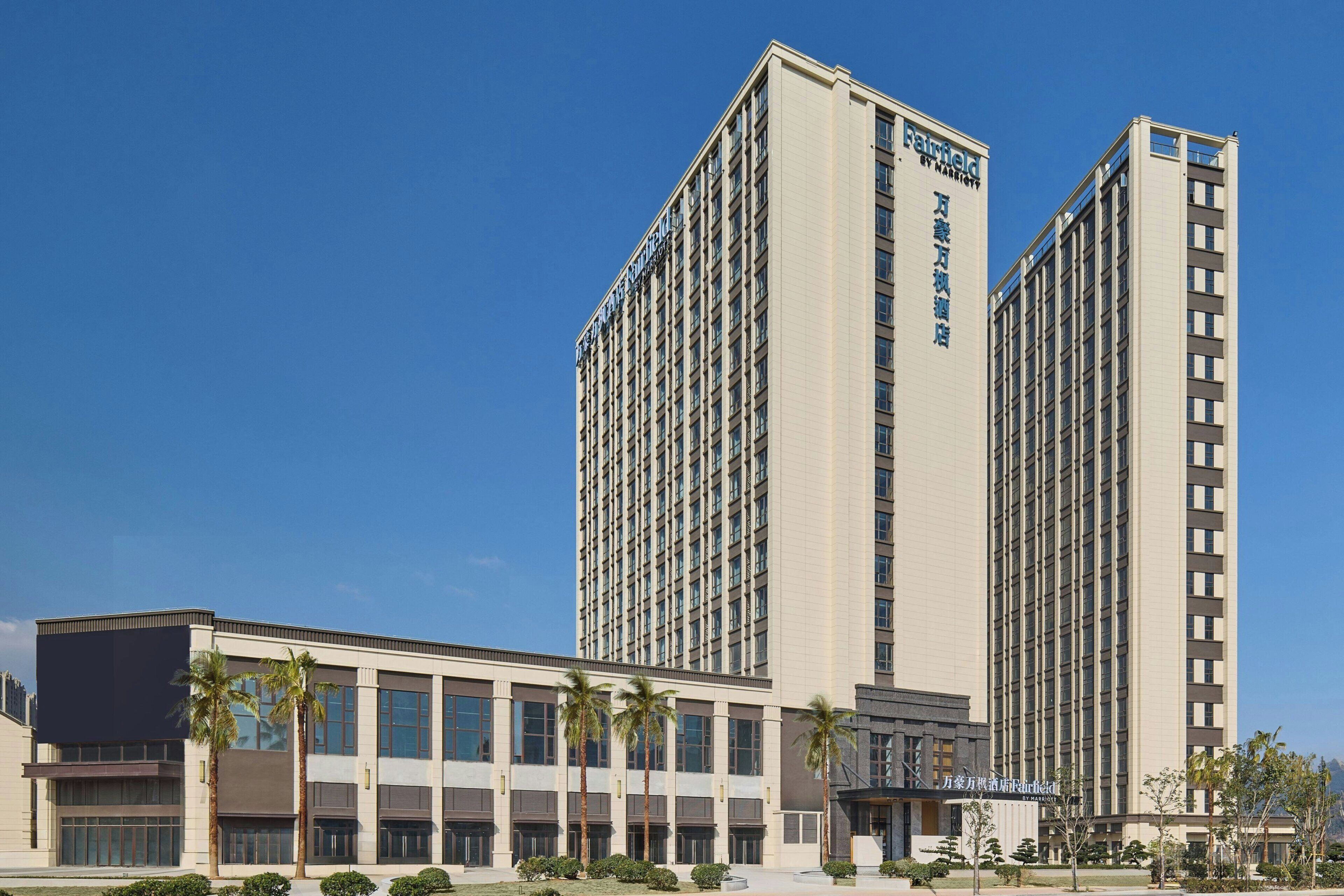 A high-rise hotel with multiple floors, a modern facade, and a clear blue sky in the background.