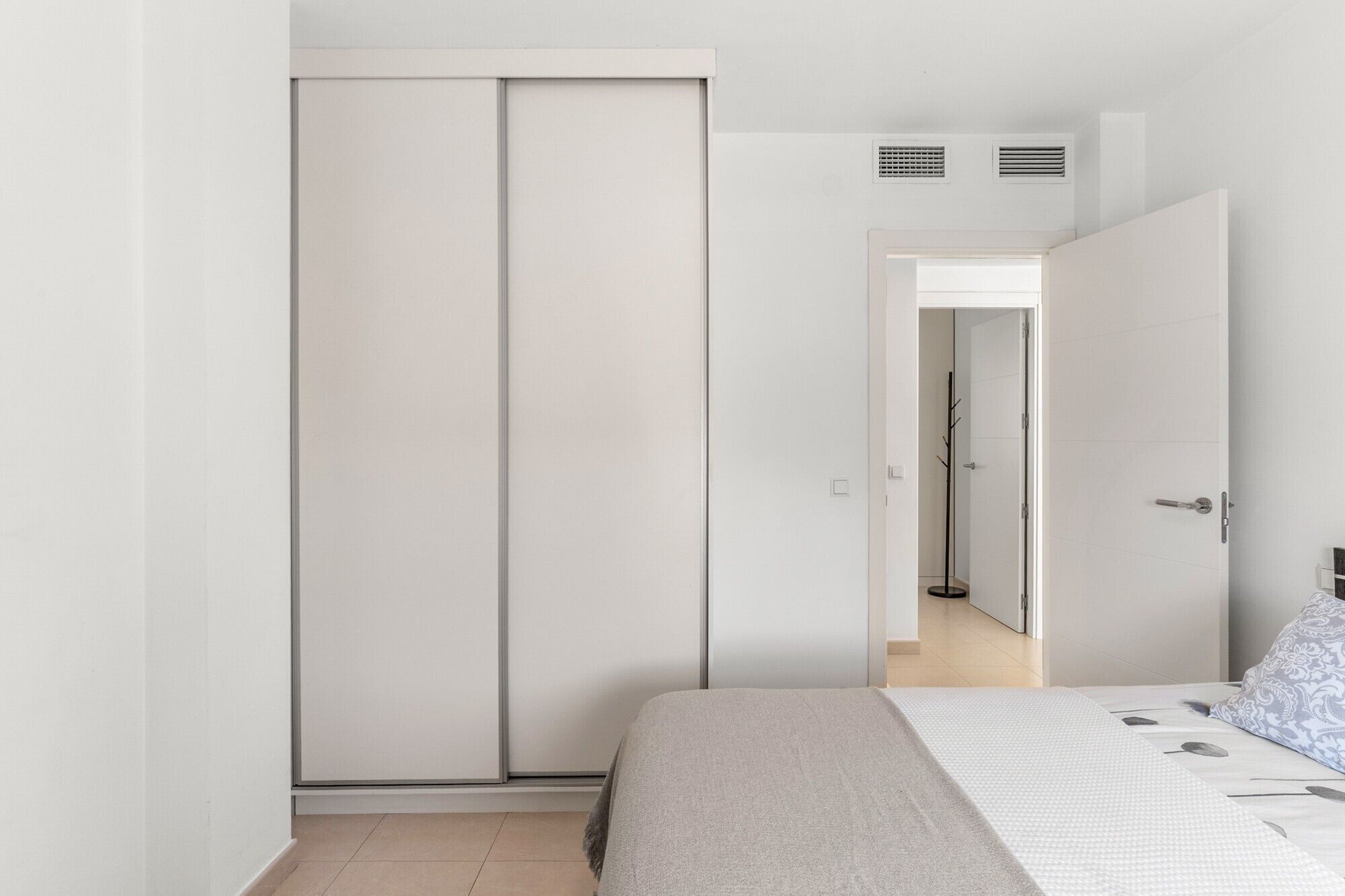 A bedroom with a bed, a wardrobe, and a door leading to another room.
