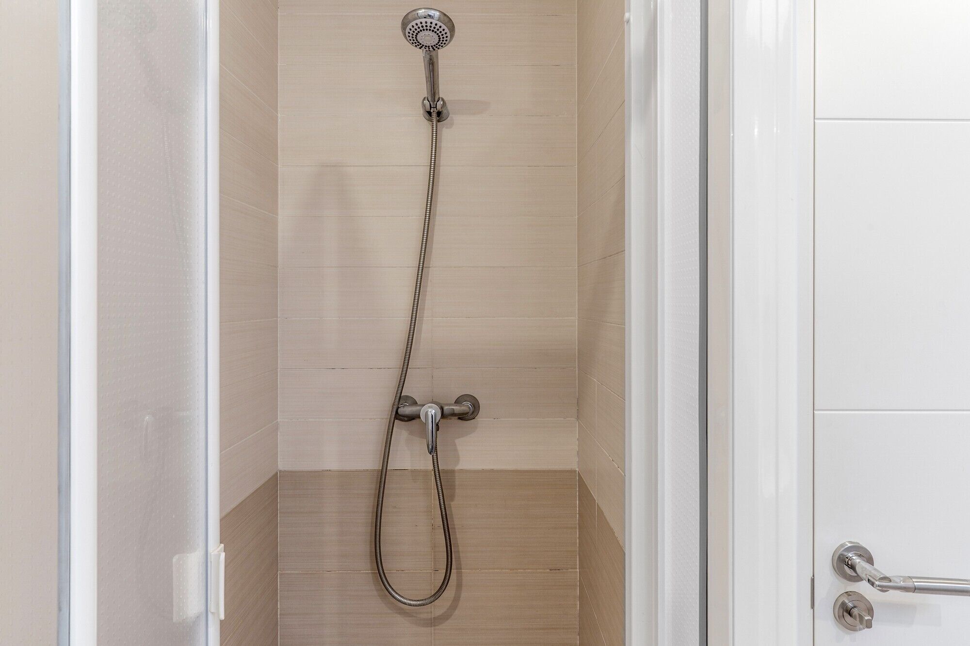 A shower with a handheld showerhead and a wall-mounted faucet.