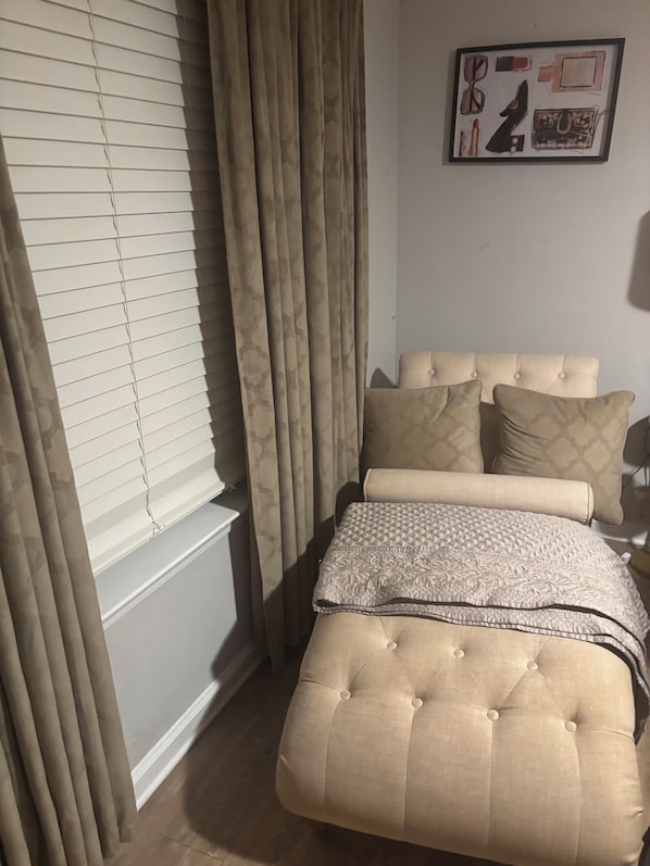 A bedroom with a bed, curtains, a headboard, and a framed picture on the wall.