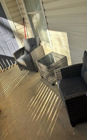 A covered outdoor seating area with wicker furniture and a concrete floor.