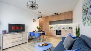 Ein modernes Wohnzimmer mit Fernseher, Sofa und Essbereich.