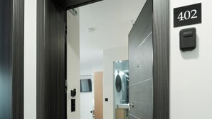 A hallway with a door marked 402, leading to a bathroom with a mirror and sink. - Tower 15 | Deluxe Studio 402 (Thessaloniki)