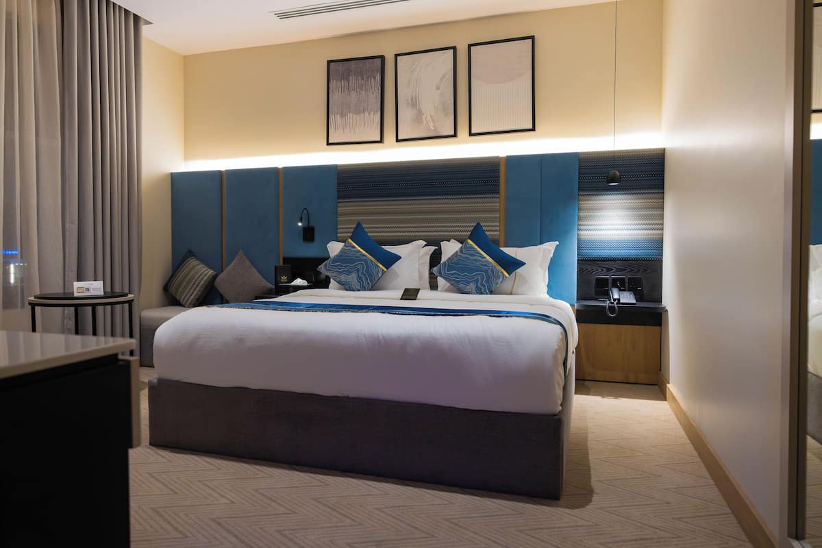 Een hotelkamer met een groot bed, nachtkastjes, een bureau en uitzicht op de stad.