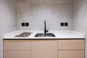 A modern kitchen with a white countertop, a black faucet, and a built-in oven. - Lamar Park Hotel Al Olaya (Tabuk)