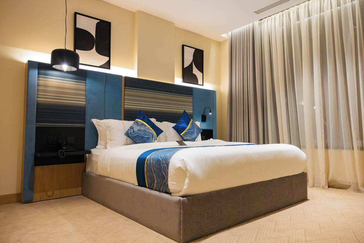 Een moderne hotelkamer met een groot bed, een nachtkastje en een wandlamp.