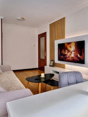 Una sala de estar moderna con un televisor de pantalla plana, un sofá, una mesa de centro y un revestimiento de pared de madera.