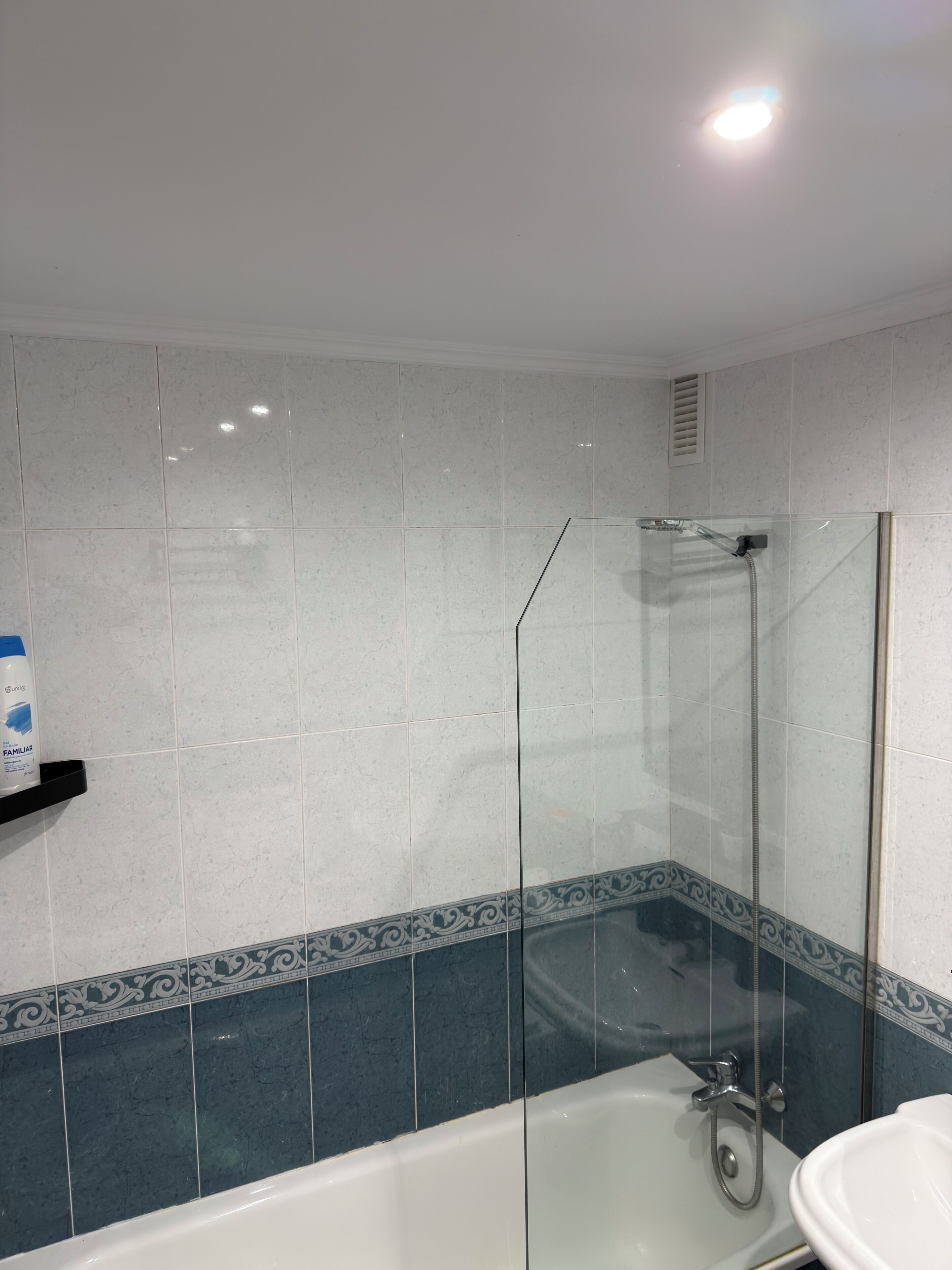 A bathroom with a glass-enclosed shower, a white bathtub, and a white sink.