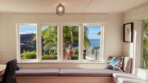 Ein Zimmer mit einer integrierten Sitzbank, einem Schreibtisch und Blick auf das Meer und die Hügel.