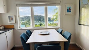 Ein Essbereich mit Tisch und Stühlen, ein Fenster mit Blick auf Hügel und Wasser sowie eine Karte an der Wand.