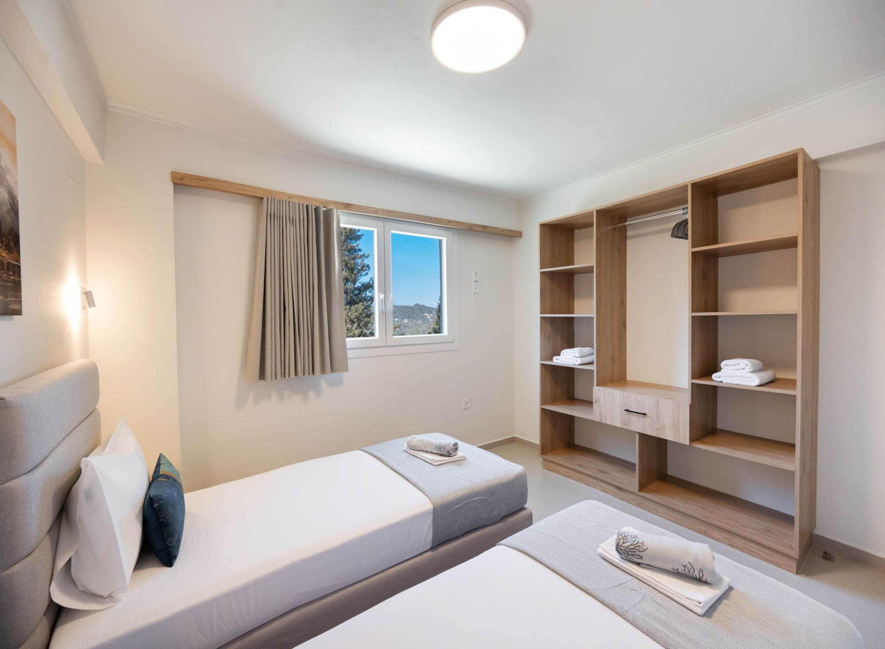 A bedroom with a bed, a bedside table, a wardrobe, and a window with curtains.