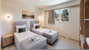 Ein Hotelzimmer mit zwei Betten, einem Bild an der Wand, einem Fenster mit Vorhängen und einem Kleiderschrank.