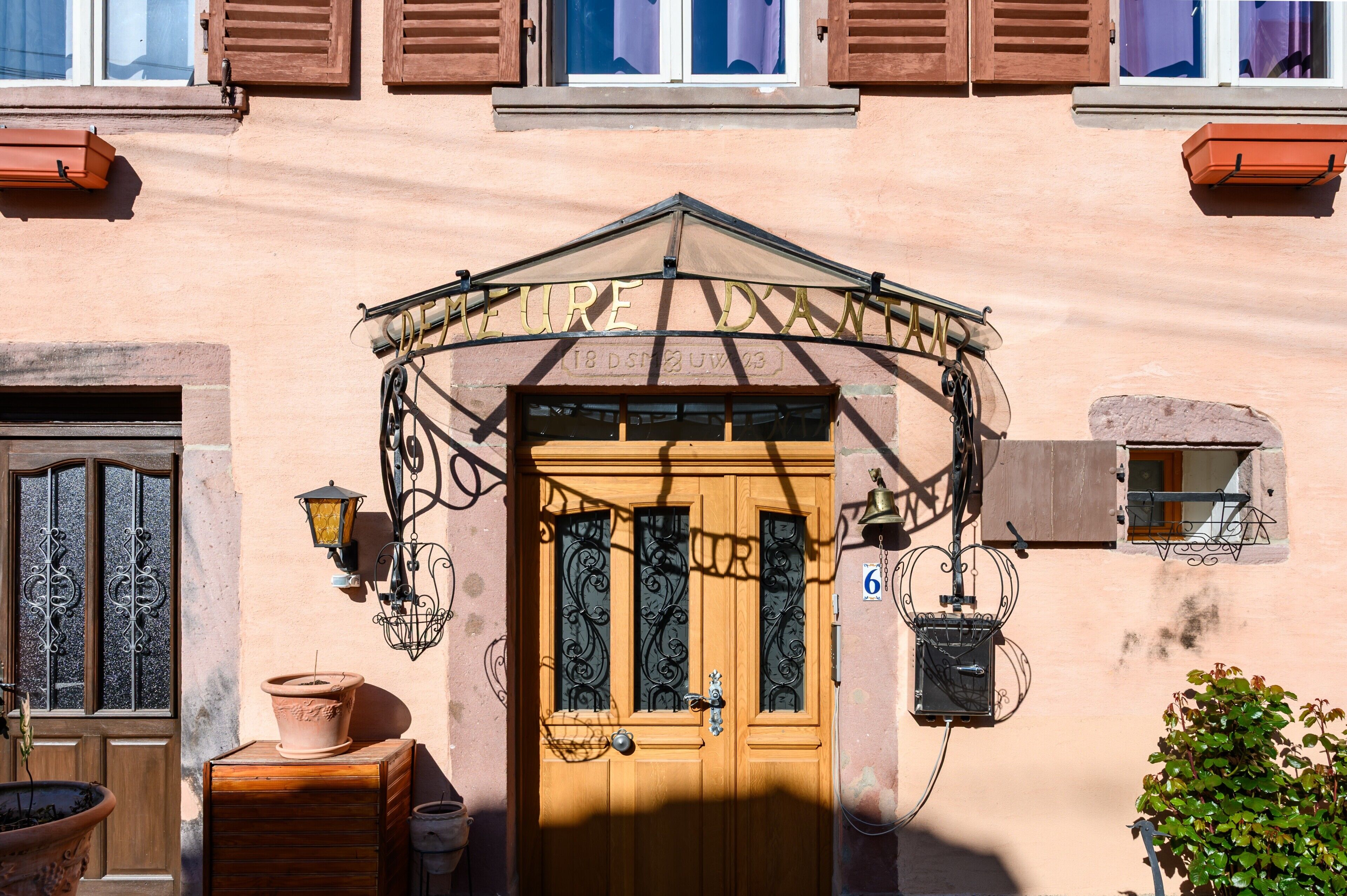 A building with a wooden door, a balcony, and a window with shutters.